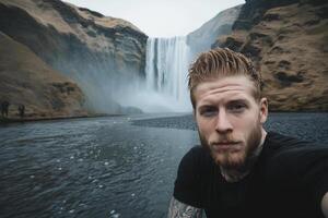 Man taking selfie in front of waterfall photo