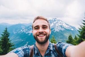 A man taking a selfie with a mountain in the background photo