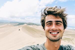 A man taking a selfie in front of a sand dune photo