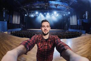 A man taking a selfie in front of a stage photo