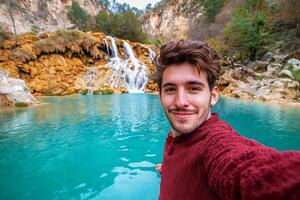 A man taking a selfie in front of a waterfall photo