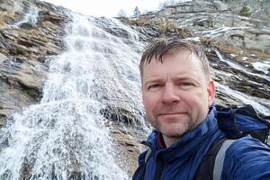 A man taking a selfie in front of a waterfall photo