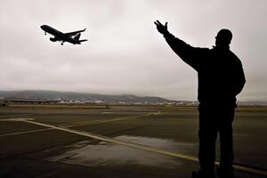 A man is standing on a runway pointing at an airplane photo