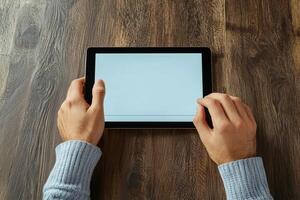 Hands holding a tablet computer on a wooden table photo