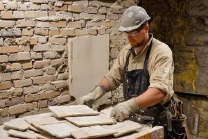 A man in an apron is working on a brick wall photo