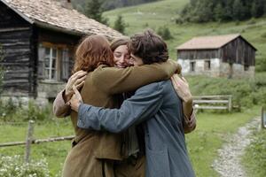 Three people hugging in front of a cabin photo