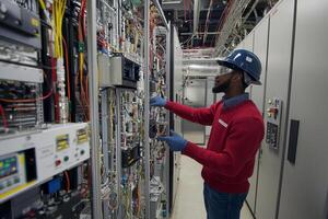 A man in a red shirt and blue gloves is working on a computer photo