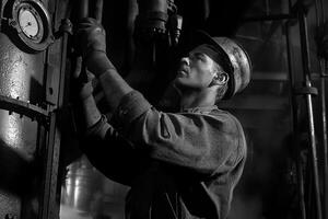 A black and white photo of a man working on a machine