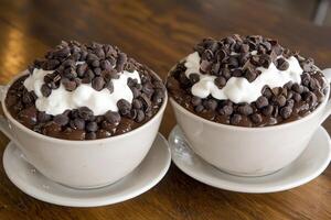 Two cups of chocolate pudding topped with whipped cream photo