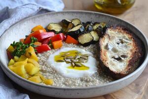 A bowl of quinoa with vegetables and bread photo