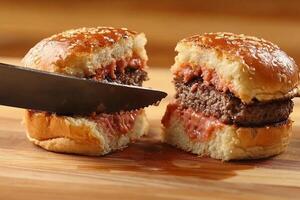 A knife is cutting into a hamburger photo