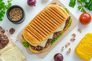 A sandwich with cheese, meat and vegetables on a cutting board photo