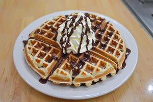 A waffle with whipped cream and chocolate syrup photo