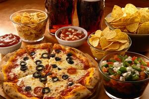 A pizza, chips, and soda on a table photo