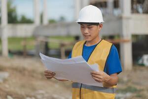 Engineering Consulting People on construction site holding blueprint in his hand. Building inspector. Construction site check drawing and business workflow of new building photo
