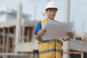 Engineering Consulting People on construction site holding blueprint in his hand. Building inspector. Construction site check drawing and business workflow of new building photo