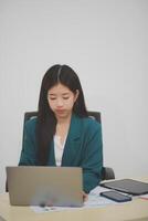 Beautiful Asian businesswoman work using a tablet and a laptop with documents placed at the office. photo