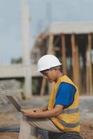 Asian man architect holds blueprint with skyscraper background, Asian male architect builder engineer design working planning confident outdoors in construction site. photo