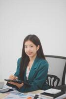 Beautiful Asian businesswoman work using a tablet and a laptop with documents placed at the office. photo