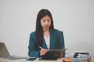 Asian business woman working using laptop computer, marketing report with calculator document on table Planning to analyze financial reports Investing in an online business plan, e-commerce. photo