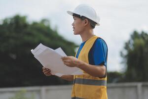 Engineering Consulting People on construction site holding blueprint in his hand. Building inspector. Construction site check drawing and business workflow of new building photo
