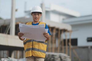 Engineering Consulting People on construction site holding blueprint in his hand. Building inspector. Construction site check drawing and business workflow of new building photo