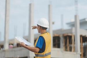 Engineering Consulting People on construction site holding blueprint in his hand. Building inspector. Construction site check drawing and business workflow of new building photo