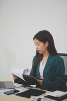 Asian business woman working using laptop computer, marketing report with calculator document on table Planning to analyze financial reports Investing in an online business plan, e-commerce. photo