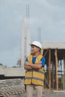 Asian man architect holds blueprint with skyscraper background, Asian male architect builder engineer design working planning confident outdoors in construction site. photo