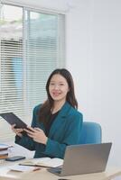 Asian professional businesswoman working on tablet computer in a corporate office photo