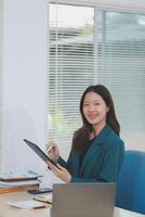 Asian professional businesswoman working on tablet computer in a corporate office photo