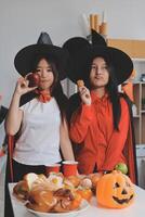 friendship, holiday and people concept - group of happy smiling friends in halloween costumes of vampire, devil, witch and cheetah at home party photo