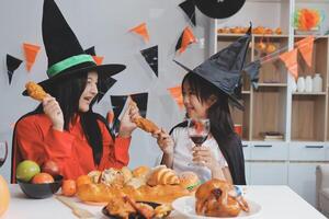 friendship, holiday and people concept - group of happy smiling friends in halloween costumes of vampire, devil, witch and cheetah at home party photo