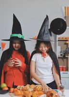 friendship, holiday and people concept - group of happy smiling friends in halloween costumes of vampire, devil, witch and cheetah at home party photo