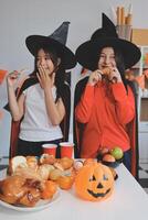 friendship, holiday and people concept - group of happy smiling friends in halloween costumes of vampire, devil, witch and cheetah at home party photo