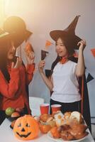 friendship, holiday and people concept - group of happy smiling friends in halloween costumes of vampire, devil, witch and cheetah at home party photo