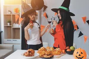 friendship, holiday and people concept - group of happy smiling friends in halloween costumes of vampire, devil, witch and cheetah at home party photo