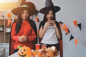 friendship, holiday and people concept - group of happy smiling friends in halloween costumes of vampire, devil, witch and cheetah at home party photo