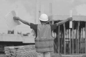 Asian man architect holds blueprint with skyscraper background, Asian male architect builder engineer design working planning confident outdoors in construction site. photo