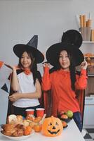 friendship, holiday and people concept - group of happy smiling friends in halloween costumes of vampire, devil, witch and cheetah at home party photo