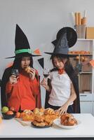 friendship, holiday and people concept - group of happy smiling friends in halloween costumes of vampire, devil, witch and cheetah at home party photo