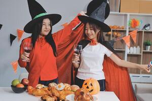 friendship, holiday and people concept - group of happy smiling friends in halloween costumes of vampire, devil, witch and cheetah at home party photo