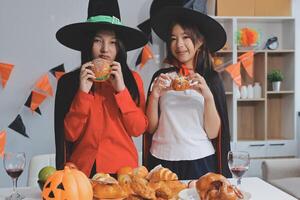 friendship, holiday and people concept - group of happy smiling friends in halloween costumes of vampire, devil, witch and cheetah at home party photo