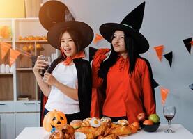 friendship, holiday and people concept - group of happy smiling friends in halloween costumes of vampire, devil, witch and cheetah at home party photo