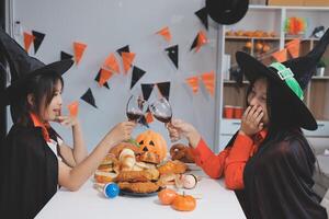 friendship, holiday and people concept - group of happy smiling friends in halloween costumes of vampire, devil, witch and cheetah at home party photo
