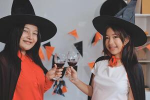 friendship, holiday and people concept - group of happy smiling friends in halloween costumes of vampire, devil, witch and cheetah at home party photo