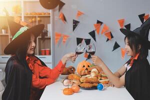 friendship, holiday and people concept - group of happy smiling friends in halloween costumes of vampire, devil, witch and cheetah at home party photo