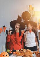 friendship, holiday and people concept - group of happy smiling friends in halloween costumes of vampire, devil, witch and cheetah at home party photo