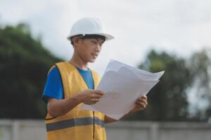 Engineering Consulting People on construction site holding blueprint in his hand. Building inspector. Construction site check drawing and business workflow of new building photo