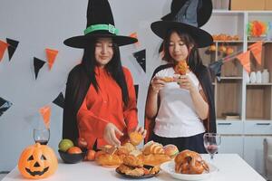 friendship, holiday and people concept - group of happy smiling friends in halloween costumes of vampire, devil, witch and cheetah at home party photo
